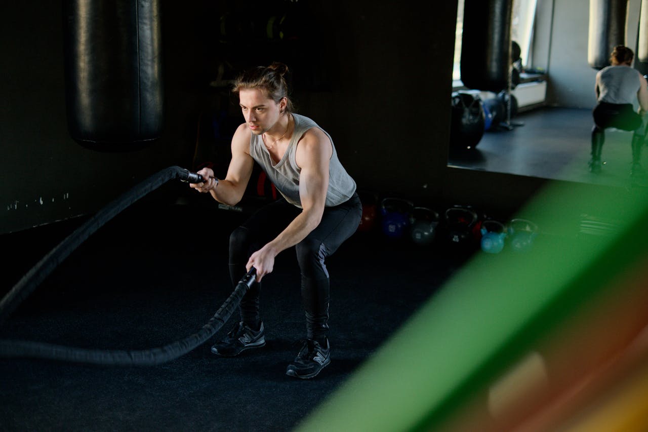 Man engages in an intense battle rope workout in a gym, focusing on fitness and strength.